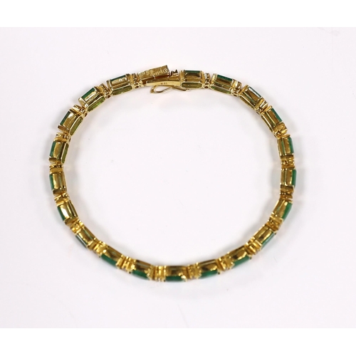 917 - A modern 18k yellow metal and twenty stone emerald set line bracelet, with diamond chip spacers, 18c... 