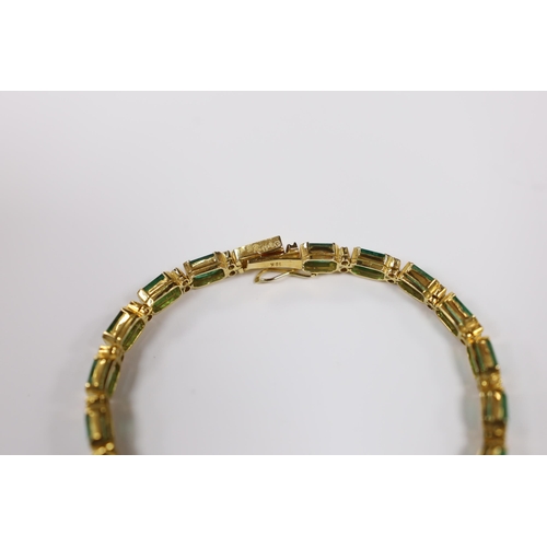 917 - A modern 18k yellow metal and twenty stone emerald set line bracelet, with diamond chip spacers, 18c... 