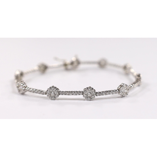 918 - A modern 18k white metal and diamond cluster set flower head line bracelet, 17.5cm, gross weight 8.4... 