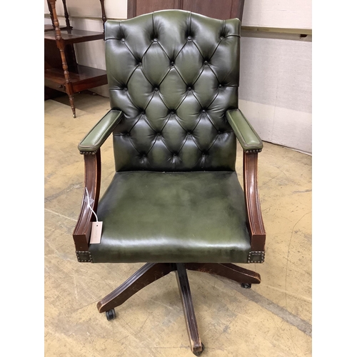 1063 - A reproduction mahogany and buttoned green leather swivel desk chair, width 60cm, depth 58cm, height... 