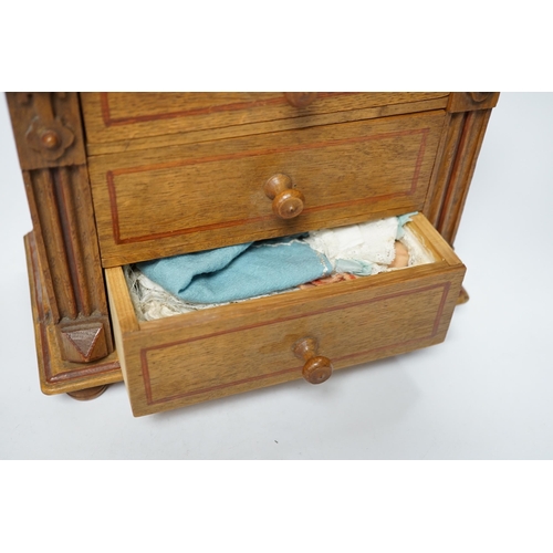 1256 - A miniature oak chest of drawers and contents (miniature bisque headed dolls and linen) height 22cm... 