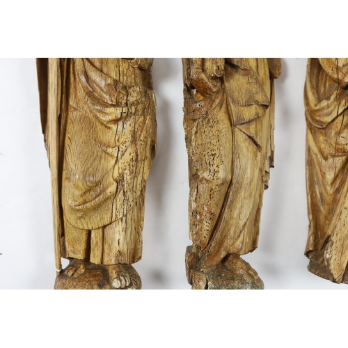 1356 - A set of three 18th century Continental carved wood figures of Saints, holding a cross, a bible and ... 