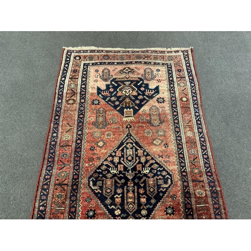 1192 - An Heriz red ground medallion rug with triple medallions on a brick red ground, multi bordered, 280 ... 