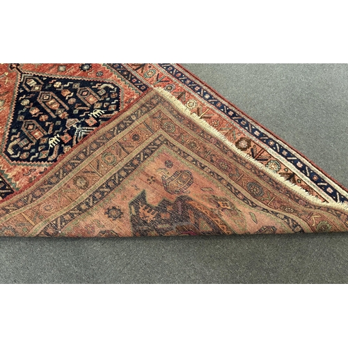 1192 - An Heriz red ground medallion rug with triple medallions on a brick red ground, multi bordered, 280 ... 