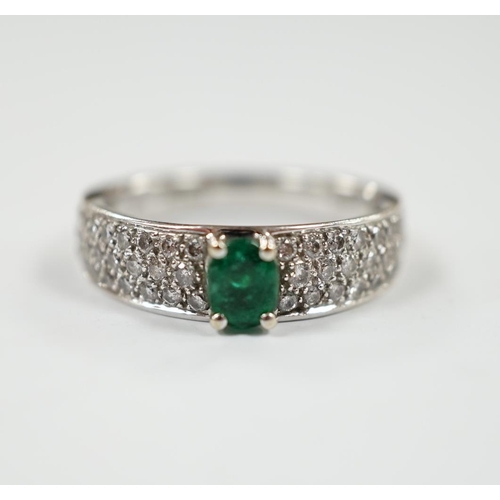 1979 - A modern 18ct white gold and single stone oval cut emerald set ring, with pave set diamond shoulders... 