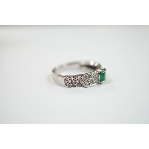 1979 - A modern 18ct white gold and single stone oval cut emerald set ring, with pave set diamond shoulders... 