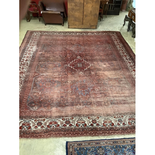 1028 - An early 20th century North West Persian red ground carpet, 410 x 348cm, worn and patch repaired.... 