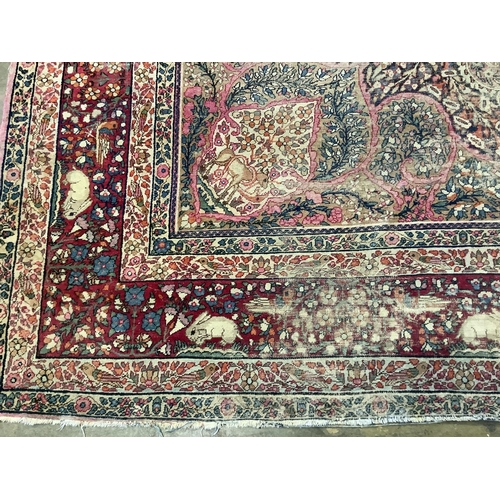 118 - An antique Kirman ivory ground pictorial carpet (severely worn), 348 x 265cm