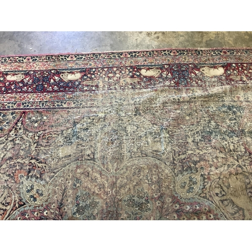 118 - An antique Kirman ivory ground pictorial carpet (severely worn), 348 x 265cm