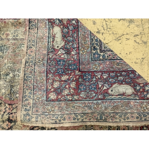 118 - An antique Kirman ivory ground pictorial carpet (severely worn), 348 x 265cm