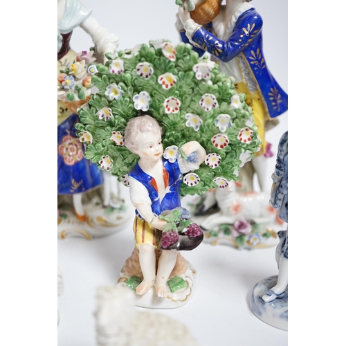 596 - A pair of Derby style porcelain small bocage figures, a boy and girl seated with grape filled hats, ... 