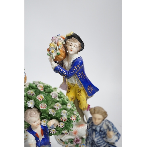 596 - A pair of Derby style porcelain small bocage figures, a boy and girl seated with grape filled hats, ... 