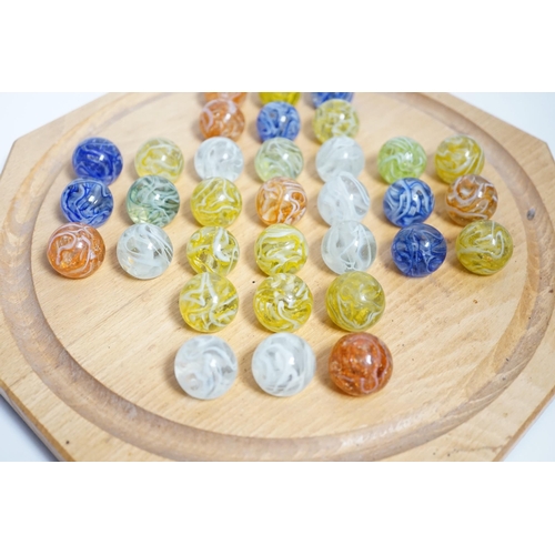 628 - A turned wood solitaire board with multi-coloured glass marbles, 27cm wide