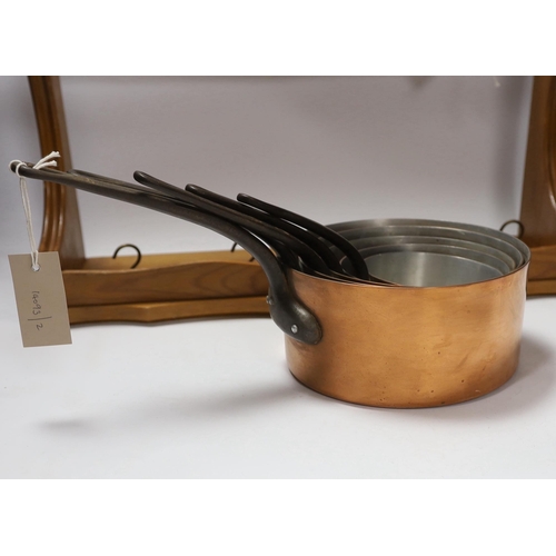 668 - A graduated set of five French copper and cast iron saucepans with pine hanging rack, 57cm wide... 