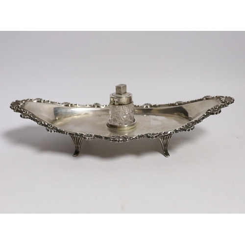 842 - A late Victorian silver navette shaped inkstand, with silver mounted cut glass well, on four reeded ... 