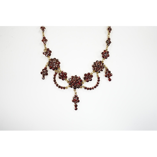 915 - An early 20th century gilt sterling and garnet cluster set drop necklace, 45cm.