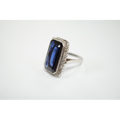 925 - A 1920's white metal and single stone emerald cut synthetic sapphire set dress ring, with millegrain... 