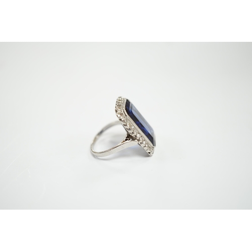 925 - A 1920's white metal and single stone emerald cut synthetic sapphire set dress ring, with millegrain... 