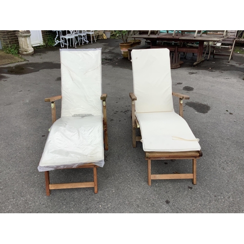 174 - A pair of John Lewis brass mounted folding teak steamer garden chairs with seat cushions