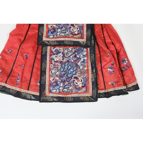 280 - A Chinese red silk skirt, embroidered with a blue silk panel of Chinese knotting flowers and auspici... 