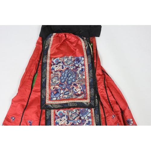 280 - A Chinese red silk skirt, embroidered with a blue silk panel of Chinese knotting flowers and auspici... 