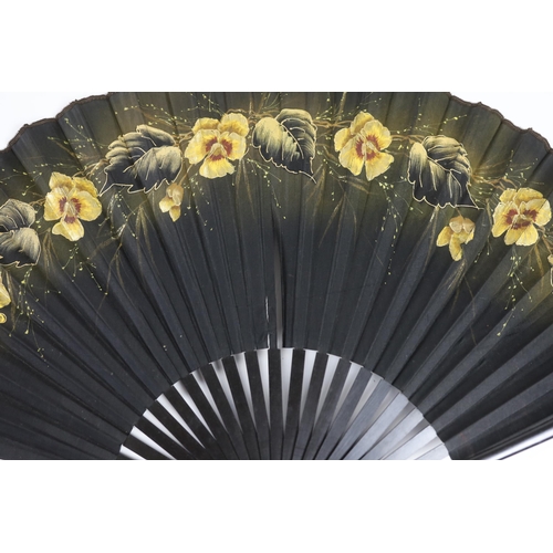 373 - Two early 20th century ebony fans, one cotton leaf, the other hand painted pansies on a fine a silk ... 