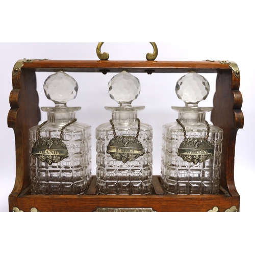 439 - A three bottle tantalus with silver mounts and engraved Masonic presentation, 36cm wide