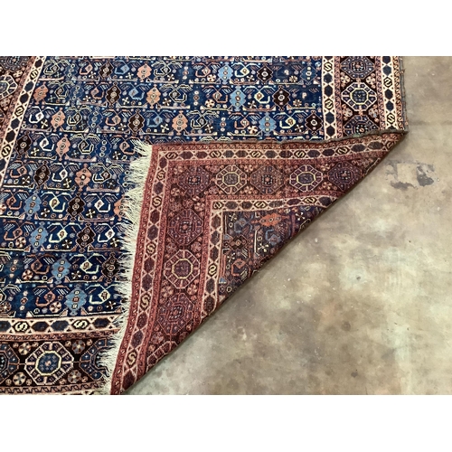 76 - A Caucasian square shaped rug, woven with rows of hooked devices and shaped lozenges, on a blue fiel... 