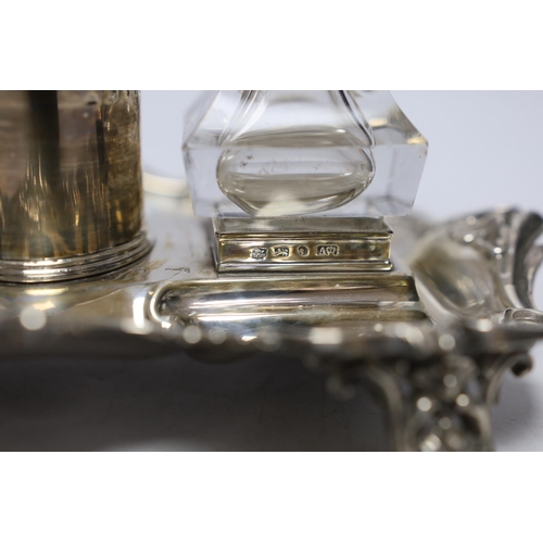 854 - An early Victorian ornate silver inkstand, with two mounted glass wells and central taperstick, Henr... 