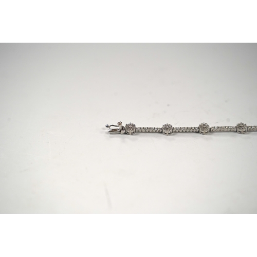 910 - A modern 18k white metal and diamond cluster set line bracelet, 17.8cm, gross weight 8.8 grams.... 