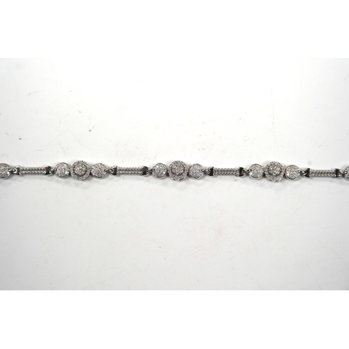 911 - A modern 14k white metal and diamond cluster set line bracelet, the total diamond weight approximate... 