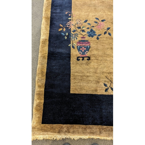 185 - A Walter Nichols Chinese champagne ground carpet with asymmetrical decoration of flowers and an urn,... 