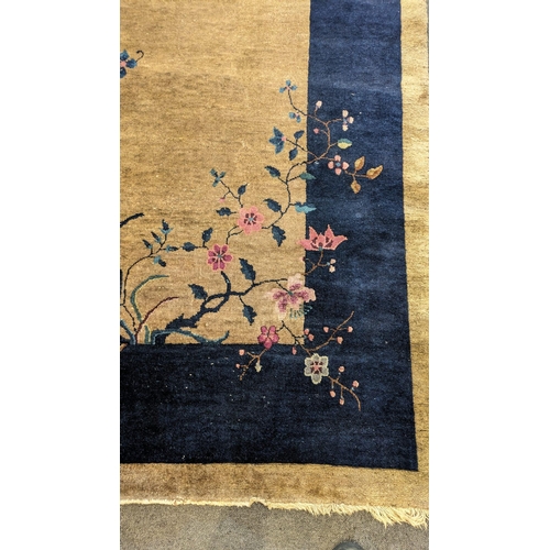 185 - A Walter Nichols Chinese champagne ground carpet with asymmetrical decoration of flowers and an urn,... 