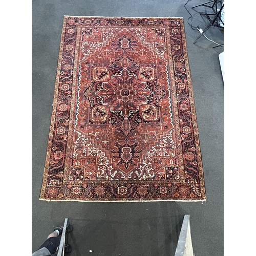 190 - An antique Heriz carpet, with central medallion on a brick red ground, multi bordered, 410 x 295cm... 