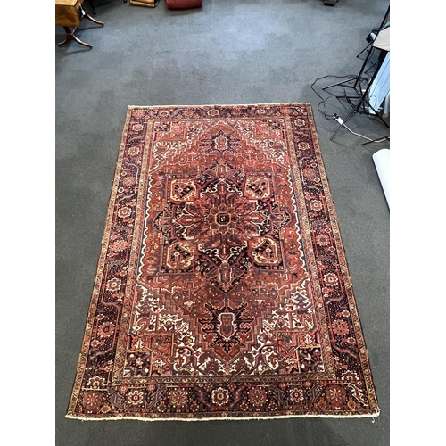 190 - An antique Heriz carpet, with central medallion on a brick red ground, multi bordered, 410 x 295cm... 