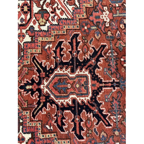 190 - An antique Heriz carpet, with central medallion on a brick red ground, multi bordered, 410 x 295cm... 