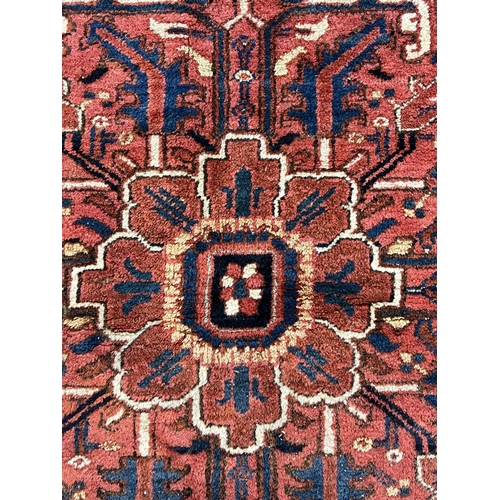 190 - An antique Heriz carpet, with central medallion on a brick red ground, multi bordered, 410 x 295cm... 