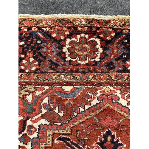 190 - An antique Heriz carpet, with central medallion on a brick red ground, multi bordered, 410 x 295cm... 