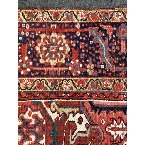 190 - An antique Heriz carpet, with central medallion on a brick red ground, multi bordered, 410 x 295cm... 