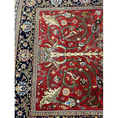 194 - A Kashan red ground rug, woven with scrolling foliage and birds within a dark border, 216 x 138cm... 