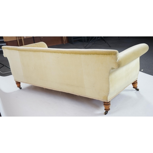 216 - A large Victorian sofa, in the manner of Howard & Sons, with faded velvet upholstery, on turned gold... 