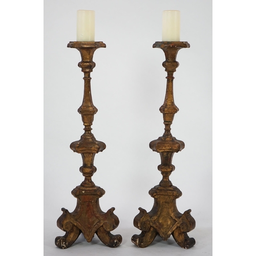 219 - A pair of 18th century Italian giltwood candlesticks with knopped triangular stems and scroll feet, ... 