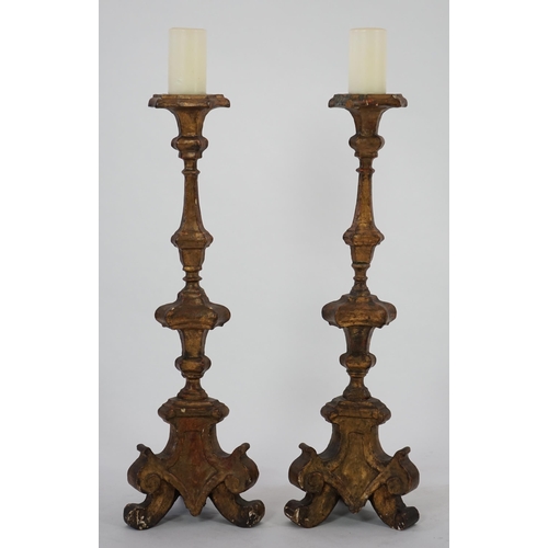 219 - A pair of 18th century Italian giltwood candlesticks with knopped triangular stems and scroll feet, ... 