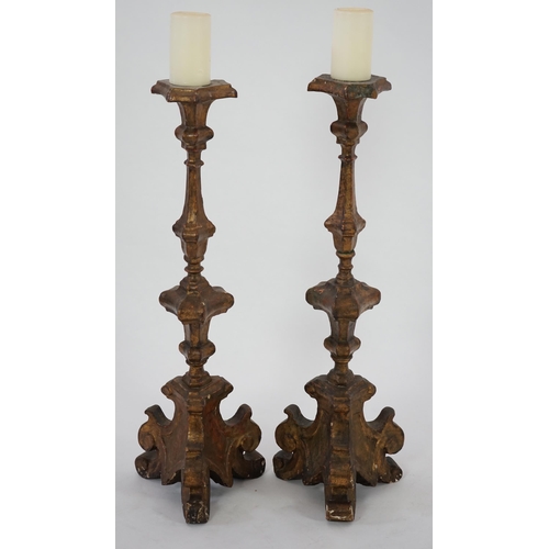 219 - A pair of 18th century Italian giltwood candlesticks with knopped triangular stems and scroll feet, ... 