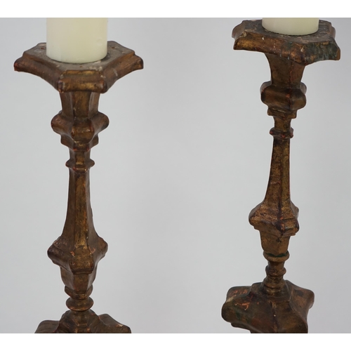 219 - A pair of 18th century Italian giltwood candlesticks with knopped triangular stems and scroll feet, ... 