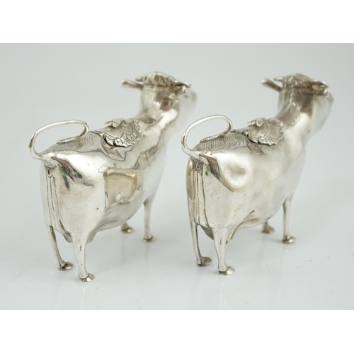 478 - A pair of Elizabeth II silver cow creamers, by Heming & Co, each with hinged cover and housefly surm... 