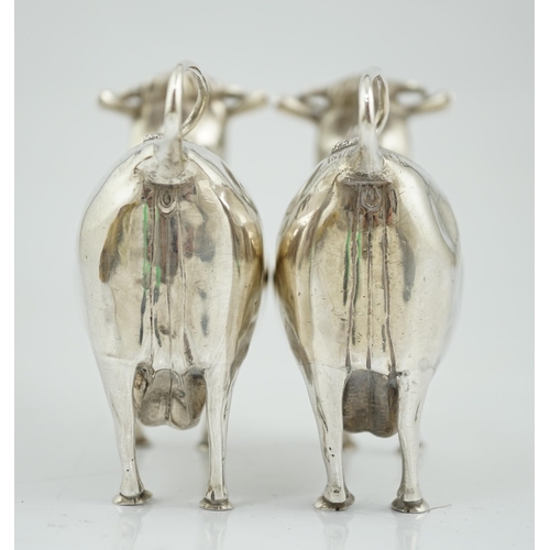 478 - A pair of Elizabeth II silver cow creamers, by Heming & Co, each with hinged cover and housefly surm... 