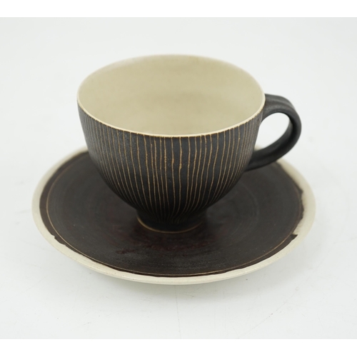 57 - Dame Lucie Rie D.B.E. (1902-1995), a manganese glazed coffee cup and saucer, the cup with incised ve... 