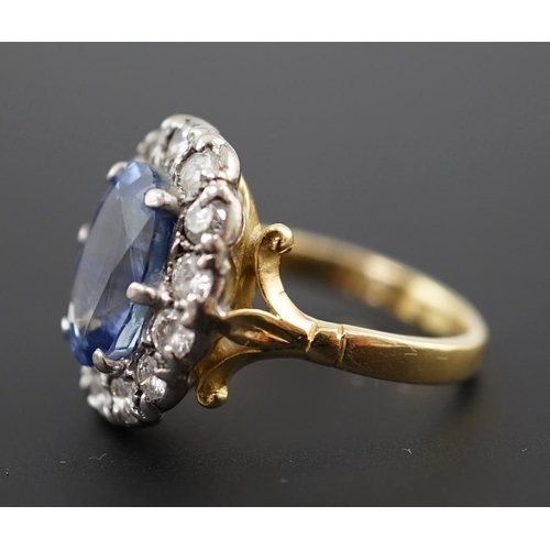 598 - An 18ct gold, sapphire and diamond set oval cluster ring, the pale blue sapphire measuring approxima... 