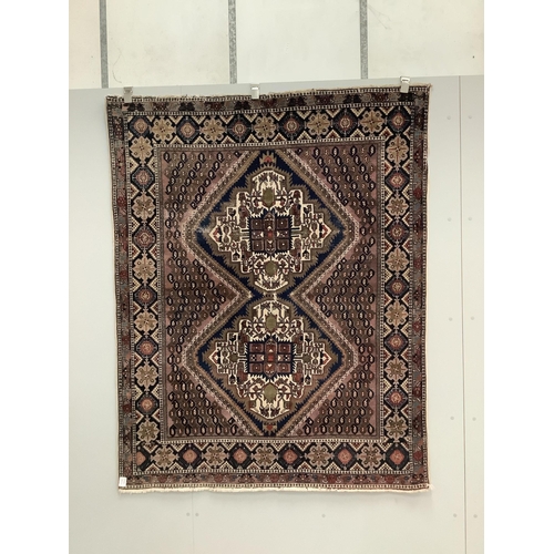 1060 - A Persian mauve ground rug, 139 x 174cm. Condition - poor
